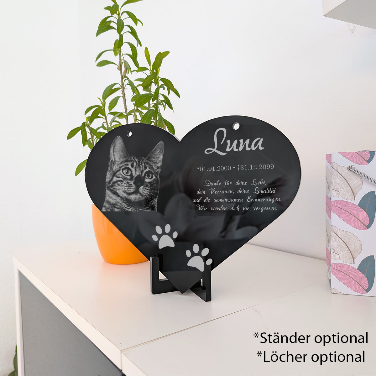 Acrylglas-Herz für Katze auf schwarzem Ständer auf einer Kommode